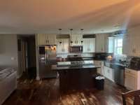 Open kitchen with custom cabinets, granite counter tops, hardwood floors, and stainless steel appliances,