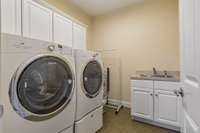 Laundry Room has a wash sink, room for sorting or hanging , & cabinets for storage.
