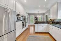 The large eat-in kitchen features custom cabinets, a walk-in pantry, and top-tier appliances, including a Wolf gas range.