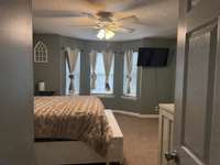 spcious primary bedroom with ceiling fan & bay window