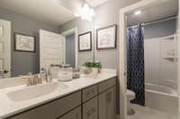Guest bath upstairs features double vanities and separation from shower.