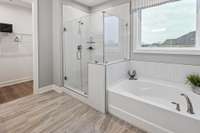 Gorgeous private bathroom in your Primary suite featuring frameless tiled walk-in shower, soaking tub, ceramic tile flooring and quartz countertops.