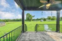 Covered rear patio overlooking serene farm like setting.