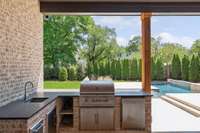 Outdoor kitchen in covered porch overlooking pool