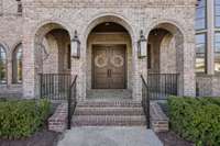 Charming Gas Lanterns, a Lovely Front Porch, and Custom Brickwork Details are an Inviting Site!
