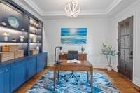 The home office is adorned with custom shelving, a high tray ceiling, and stunning hardwood floors that add warmth to the space.