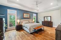 The serene primary suite features rich hardwood flooring, elegant tray ceilings, and a luxurious ensuite bathroom for the ultimate retreat.