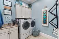 The large laundry room features it's own private sink and beautiful tile flooring,