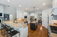 The gourmet kitchen showcases a spacious island, crisp white cabinetry, and premium Jenn Air appliances—perfectly blending style and functionality.
