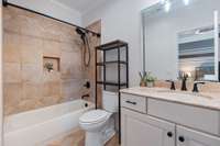 The second bathroom is enhanced by lighting above the mirror and light-toned tilework, creating a bright and inviting atmosphere.