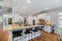 The gourmet kitchen showcases a spacious island, crisp white cabinetry, and premium Jenn Air appliances—perfectly blending style and functionality!