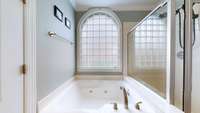 Primary suite tub and separate shower with natural light