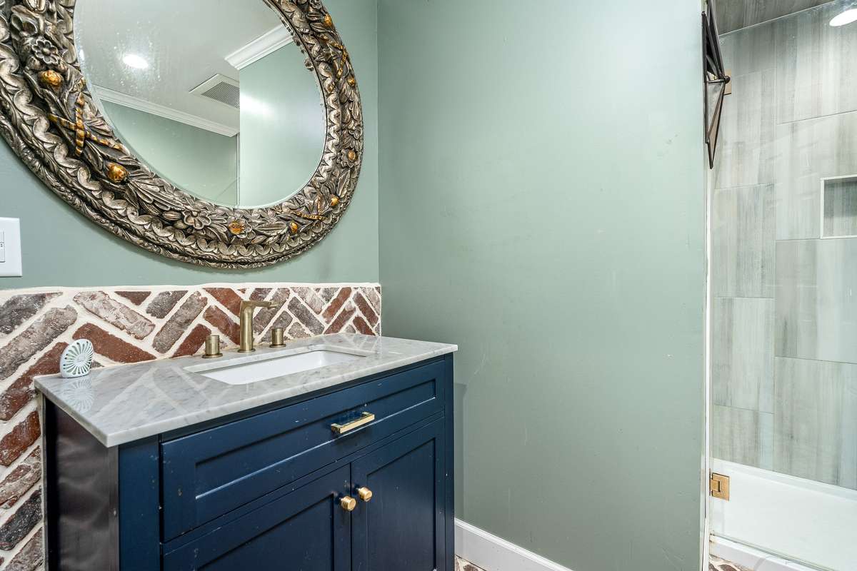 Full Bath just off the garage area with Brick accent wall, next to the Kitchen