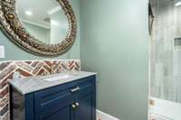 Full Bath just off the garage area with Brick accent wall, next to the Kitchen