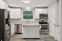 Stainless steel appliances and large sink overlooking the mature tree lined backyard.