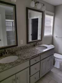 Primary bedroom with double vanities and granite counter tops.