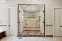 Huge step in shower witih dual shower heads and bench seating-also his and hers water closets on either side of the shower.