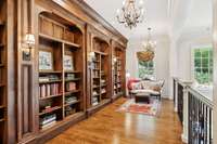 Library space with custom built in shelving, hardwood floors and custom lighting
