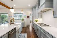 The kitchen is equipped with a gas stove, a charming farmhouse sink, and a versatile additional workspace beneath the window, perfect for meal prep or casual gatherings.