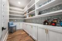 The pantry is truly a room of its own, featuring base cabinets and open shelving above—perfect for displaying jars of cookies and pasta, while storing larger kitchen essentials below.
