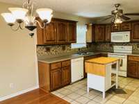 View of kitchen from dining area.  Kitchen features a tiled floor and backsplash