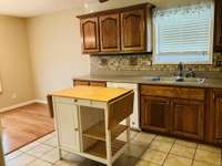 View of kitchen showing backsplash and dining area with hardwood floor