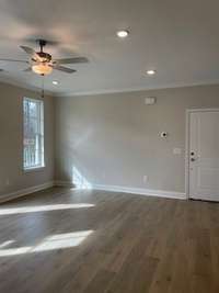 Living room with lots of natural lighting.  Laminate flooring. Lots of recessed lights. Ceiling Fan.