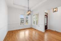 Bright and airy dining room is located on the immediate right upon entering through the front door, featuring large windows and a modern statement light fixture, perfect for gatherings and everyday meals.