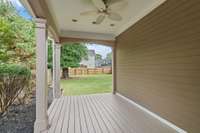 Covered back porch with recessed lighting, ceiling fan, and painted decking, perfect for relaxing or entertaining outdoors.