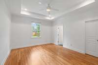 Generously sized primary bedroom with tray ceiling, recessed lighting, and backyard views, offering a peaceful private retreat.