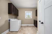 The laundry room is oversized with storage cabinets, utility closet and window.