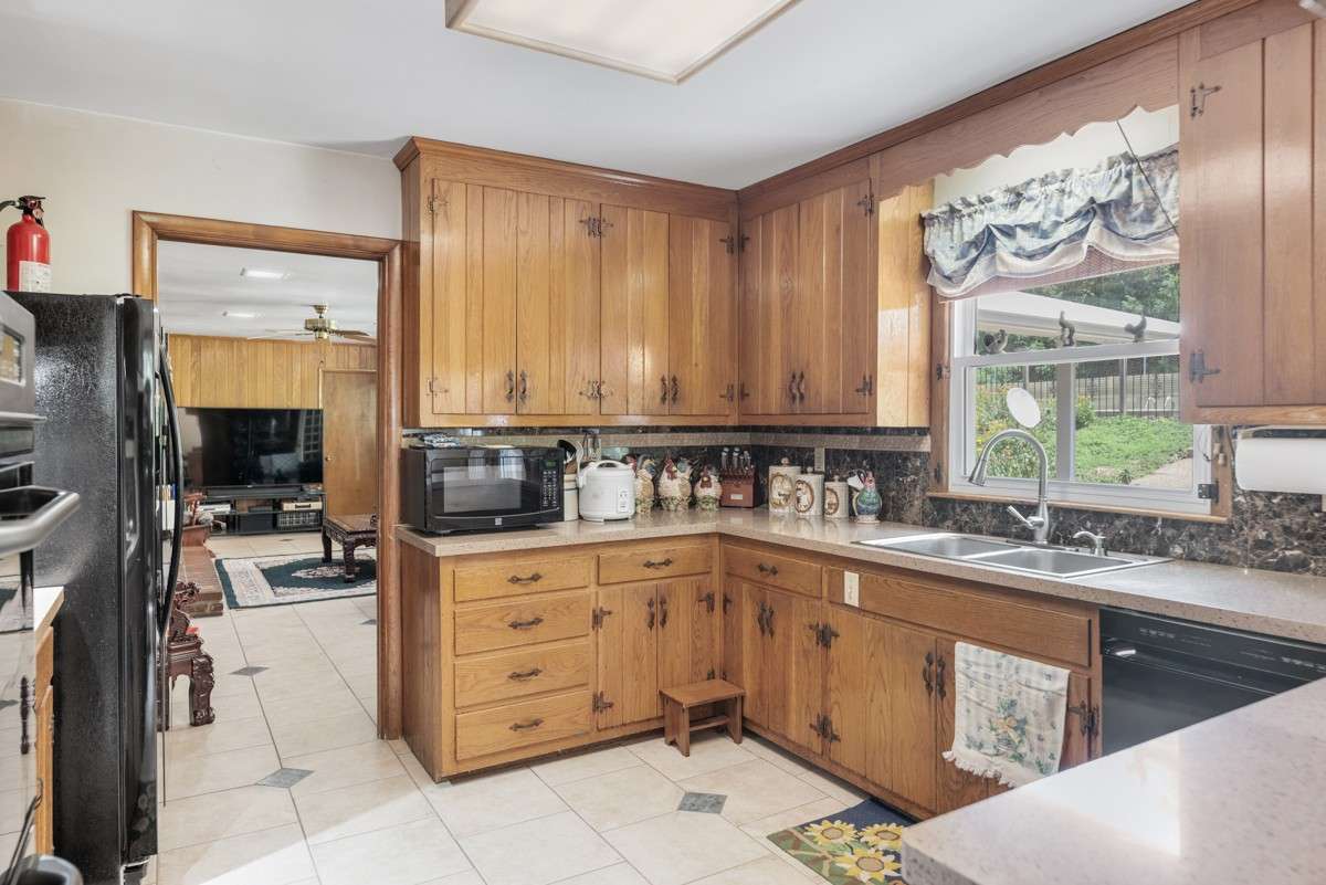 Spacious kitchen with abundant cabinetry, large countertops, and a window offering views of the backyard and pool—perfect for meal prep with a relaxing outlook.
