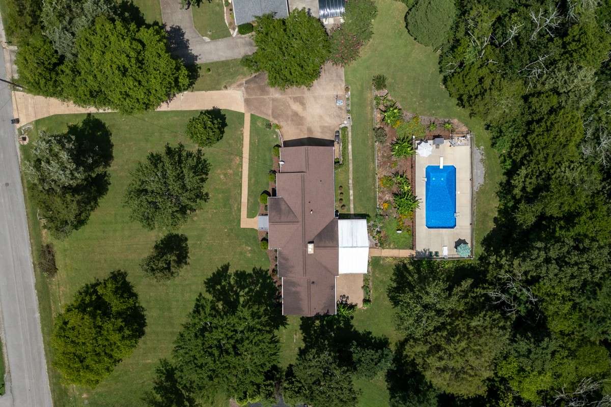 Expansive aerial view showcases the large lot, landscaped yard, covered patio, and sparkling pool—offering privacy and abundant outdoor space for relaxation or entertaining.