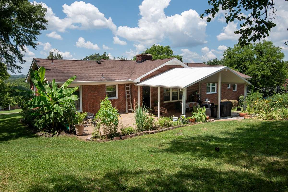 Backyard oasis featuring a covered patio, lush landscaping, and a seamless walkway leading to the pool—perfect for relaxing or entertaining outdoors.