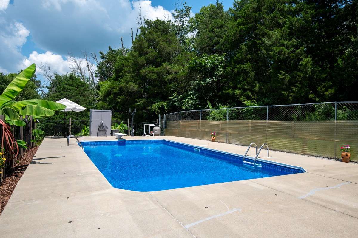 Enjoy a 33 x 16 inground pool with a diving board, surrounded by privacy fencing and lush landscaping—perfect for summer fun and relaxation.