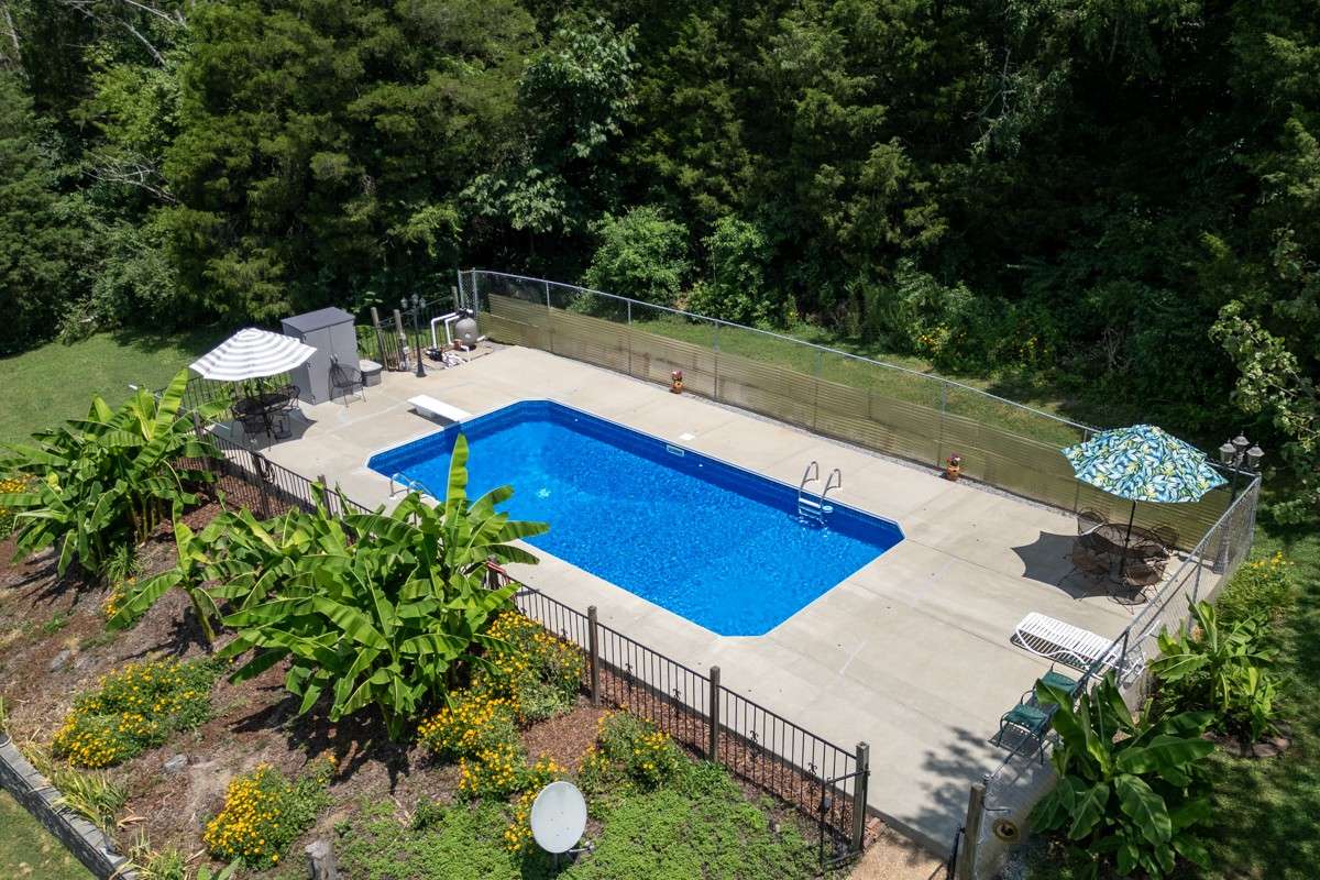 Enjoy a 33 x 16 inground pool with a diving board, surrounded by privacy fencing and lush landscaping—perfect for summer fun and relaxation.