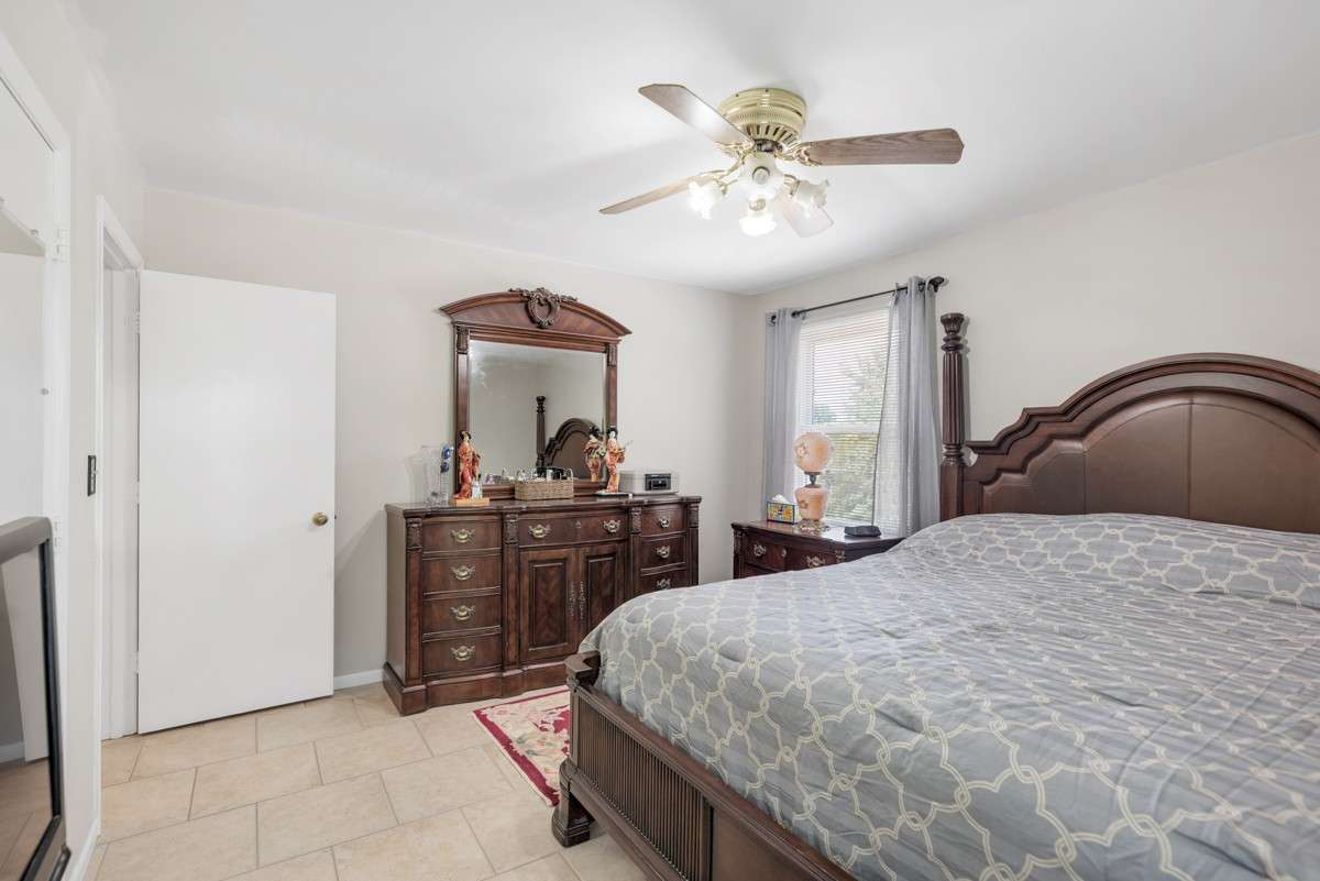 Spacious primary bedroom with abundant natural light, neutral tile floors, and an attached private bathroom for added comfort and convenience.