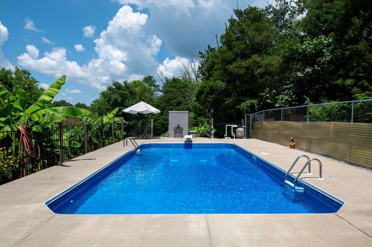 Enjoy a 33 x 16 inground pool with a diving board, surrounded by privacy fencing and lush landscaping—perfect for summer fun and relaxation.