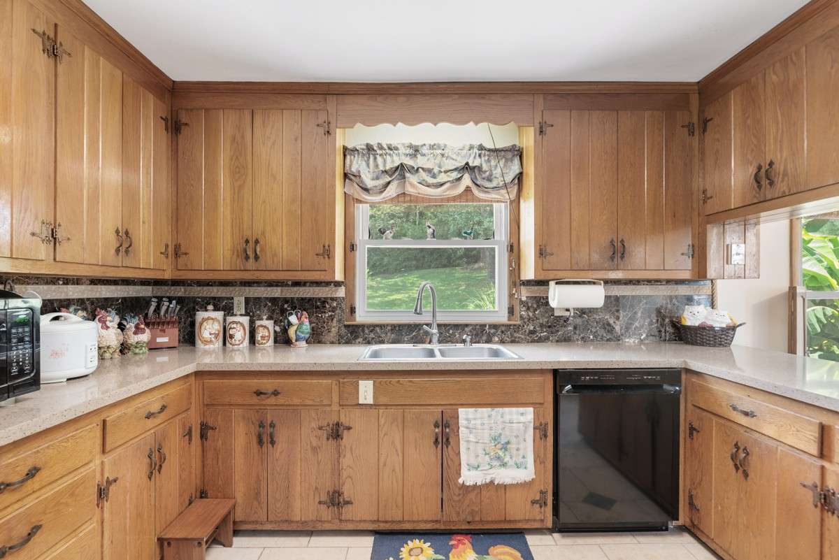 Spacious kitchen with abundant cabinetry, large countertops, and a window offering views of the backyard and pool—perfect for meal prep with a relaxing outlook.