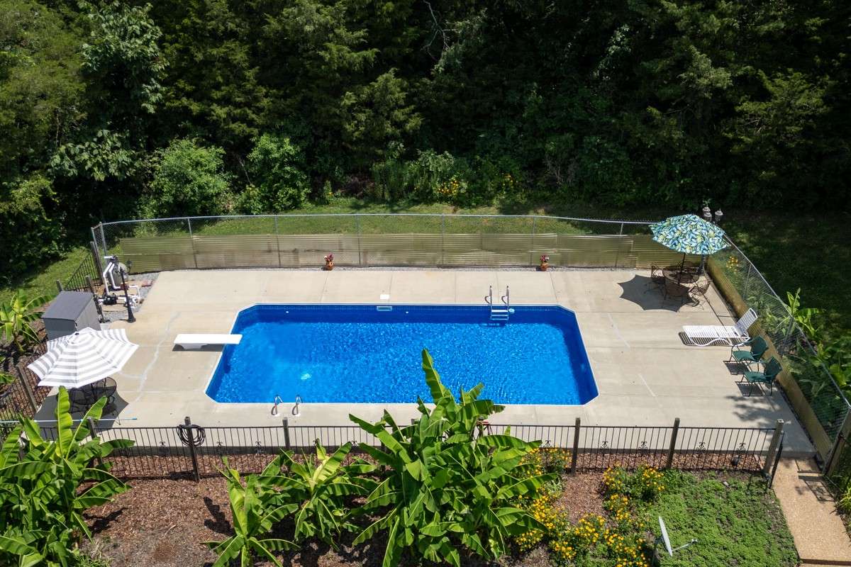 Enjoy a 33 x 16 inground pool with a diving board, surrounded by privacy fencing and lush landscaping—perfect for summer fun and relaxation.