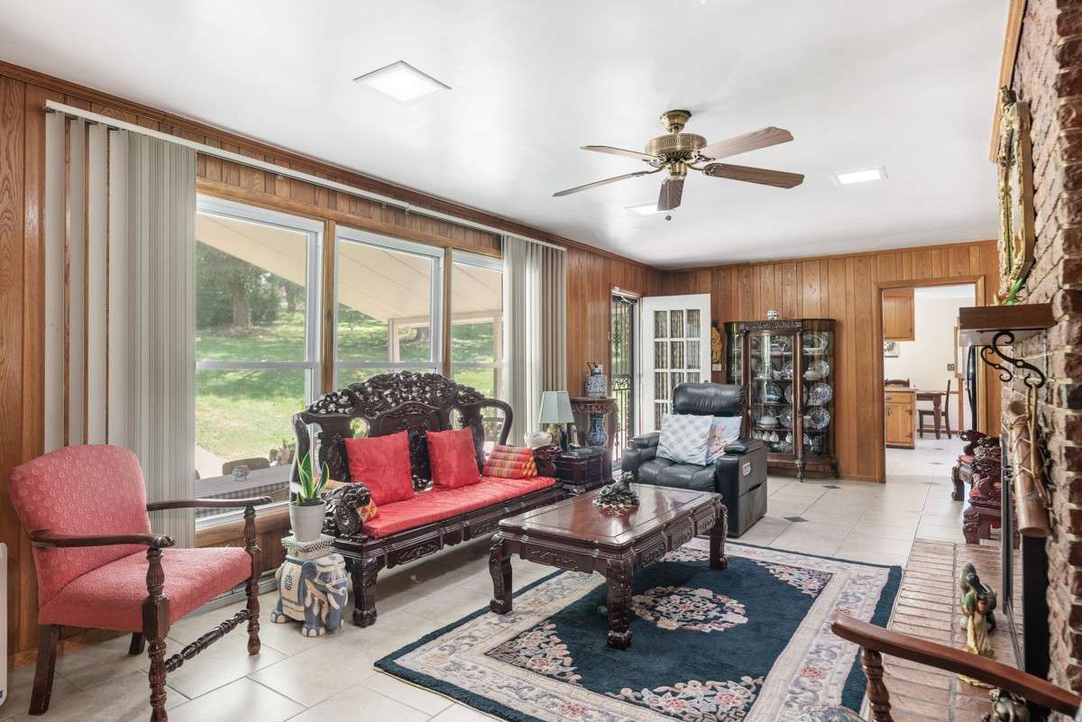 Spacious great room off the kitchen with a cozy fireplace, large windows, and easy access to the pool and covered back patio—ideal for relaxing or entertaining.