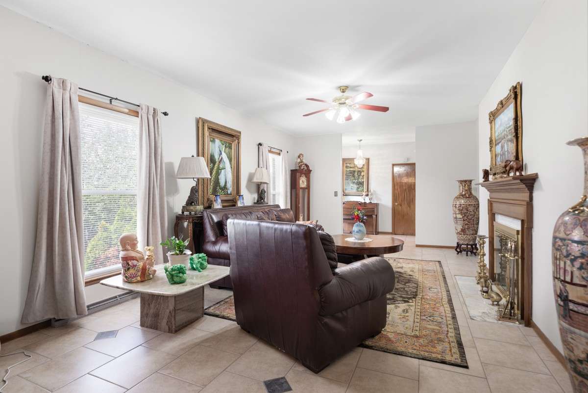 Elegant formal living room with a wood-burning fireplace flows into the formal dining room—perfect for entertaining and filled with natural light.