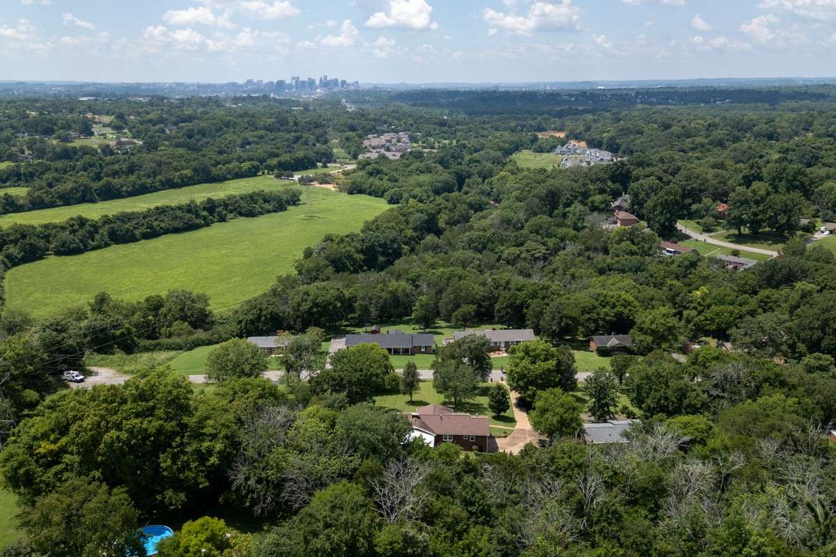 Expansive aerial view showcases the large lot, landscaped yard, covered patio, and sparkling pool—offering privacy and abundant outdoor space for relaxation or entertaining.