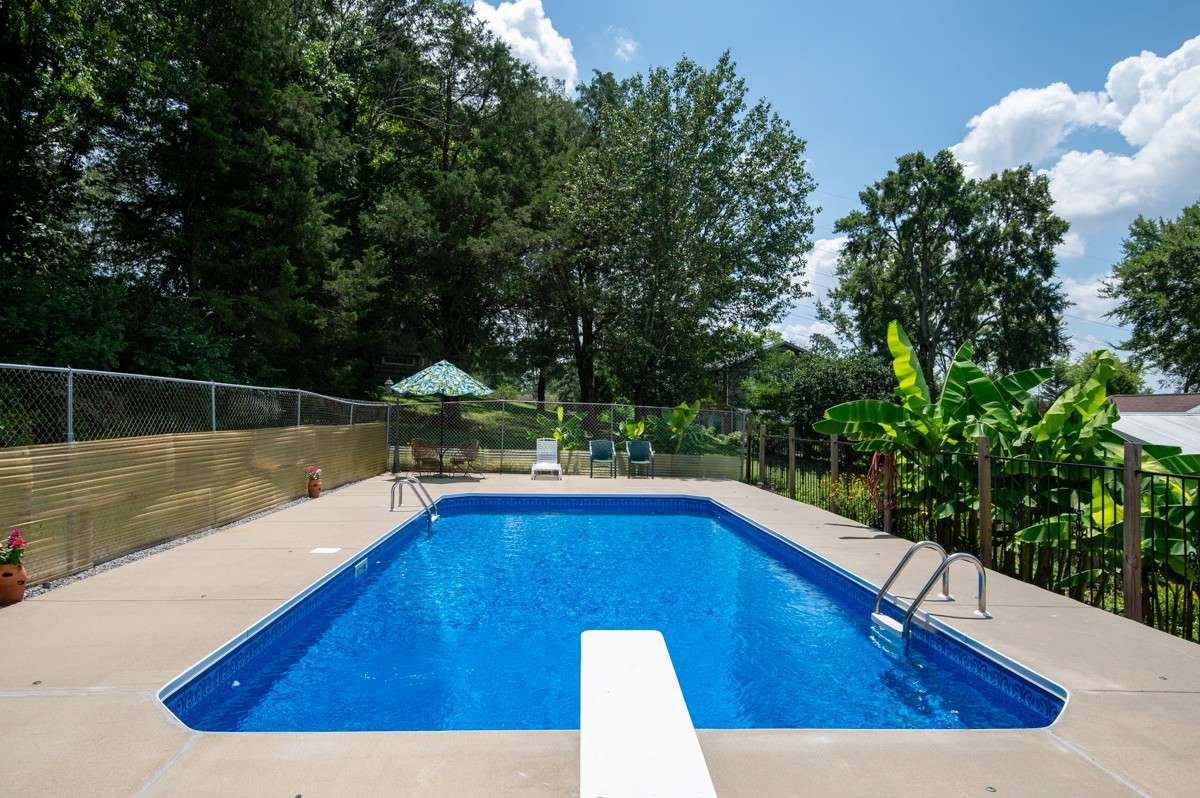 Enjoy a 33 x 16 inground pool with a diving board, surrounded by privacy fencing and lush landscaping—perfect for summer fun and relaxation.