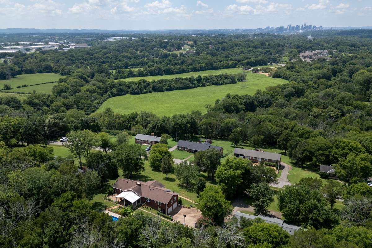 Expansive aerial view showcases the large lot, landscaped yard, covered patio, and sparkling pool—offering privacy and abundant outdoor space for relaxation or entertaining.