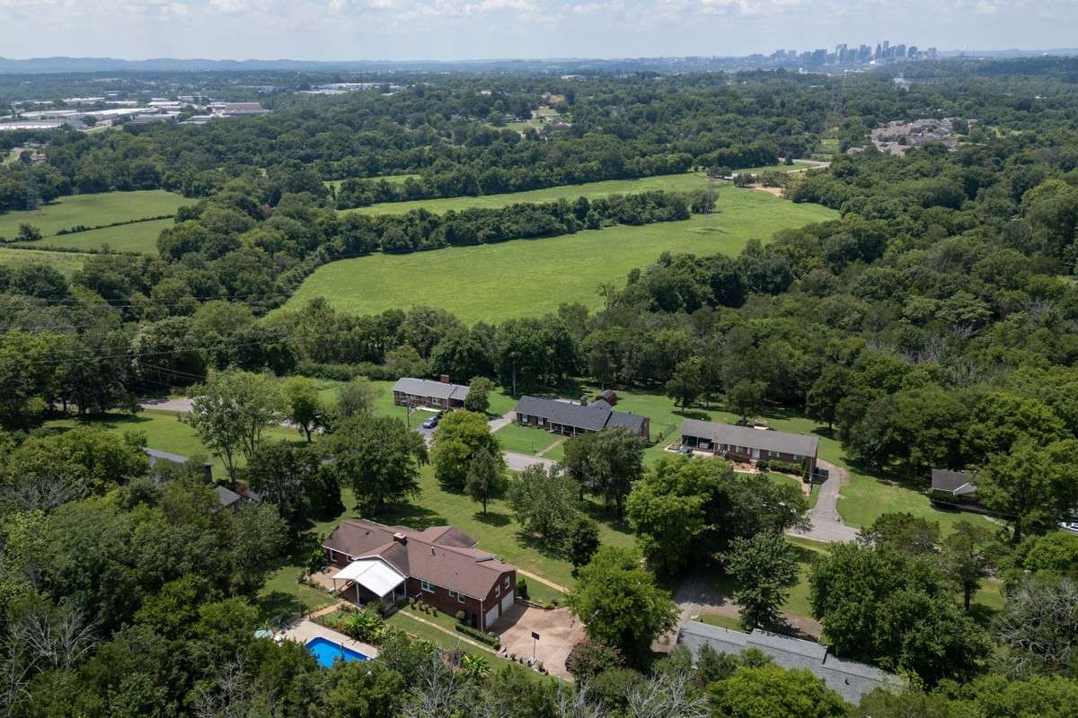 Expansive aerial view showcases the large lot, landscaped yard, covered patio, and sparkling pool—offering privacy and abundant outdoor space for relaxation or entertaining.