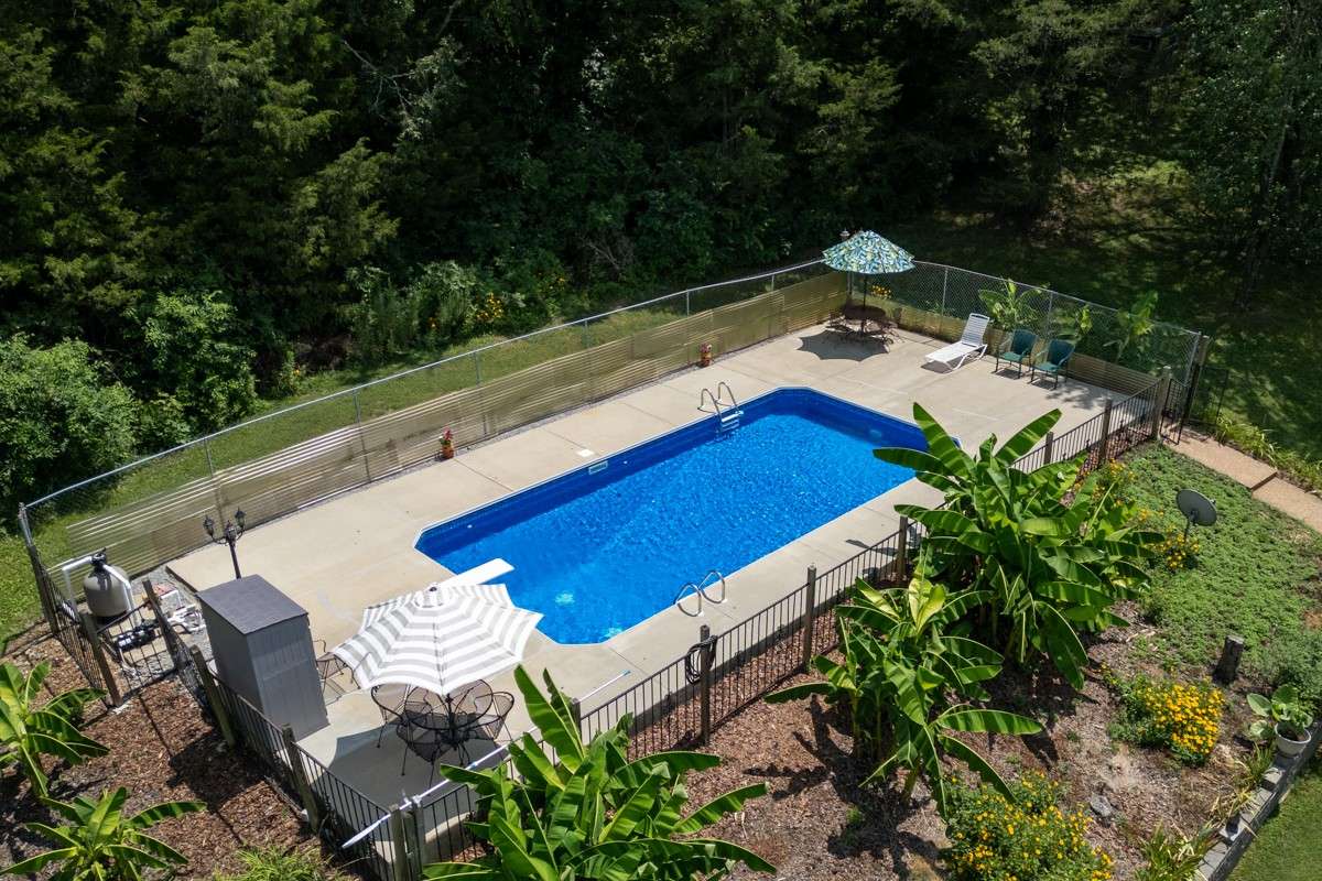 Enjoy a 33 x 16 inground pool with a diving board, surrounded by privacy fencing and lush landscaping—perfect for summer fun and relaxation.