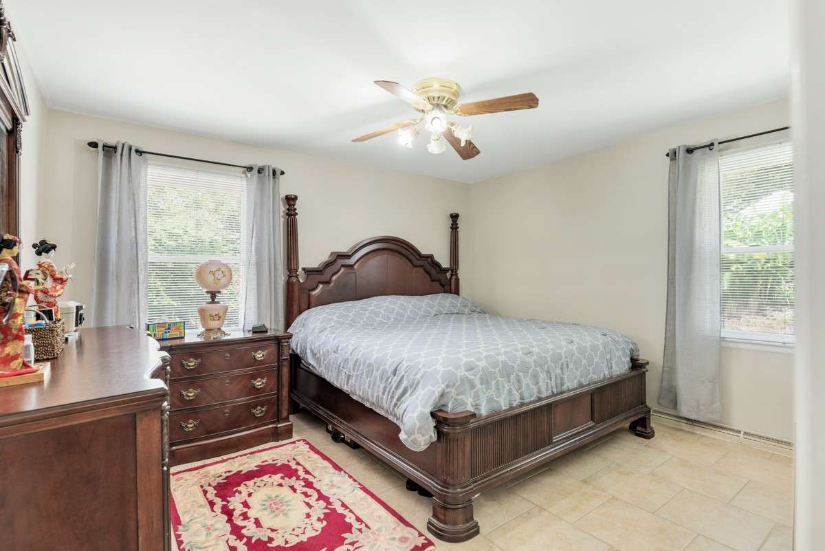 Spacious primary bedroom with abundant natural light, neutral tile floors, and an attached private bathroom for added comfort and convenience.