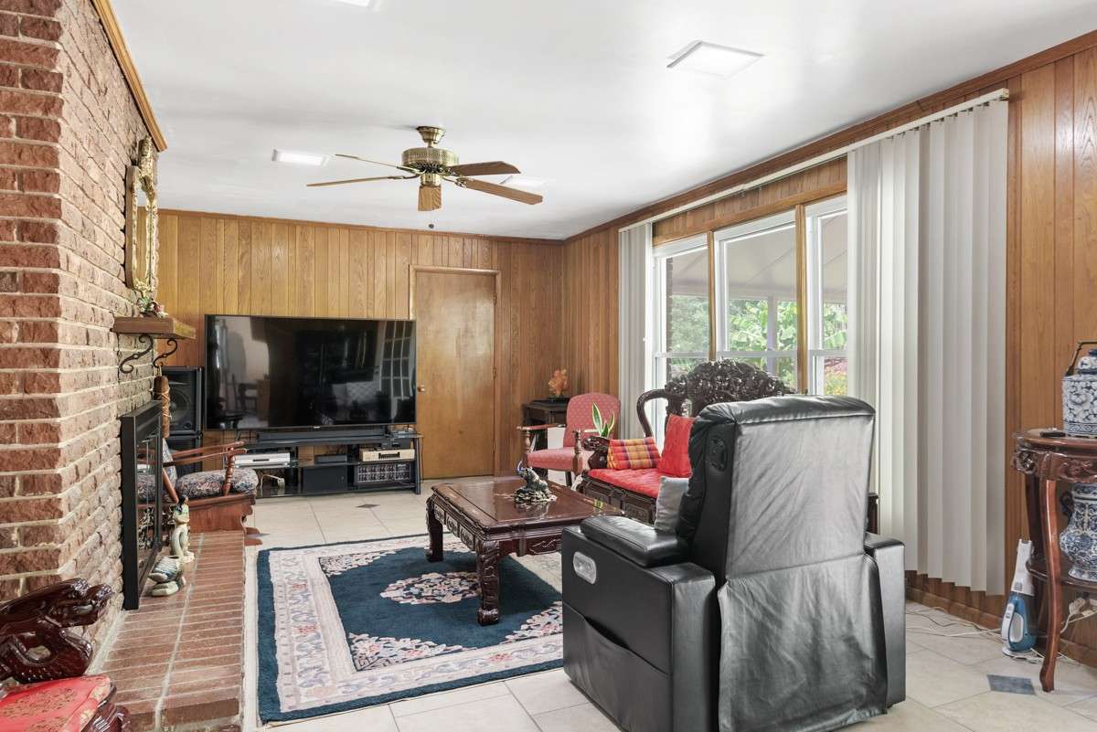 Spacious great room off the kitchen with a cozy fireplace, large windows, and easy access to the pool and covered back patio—ideal for relaxing or entertaining.