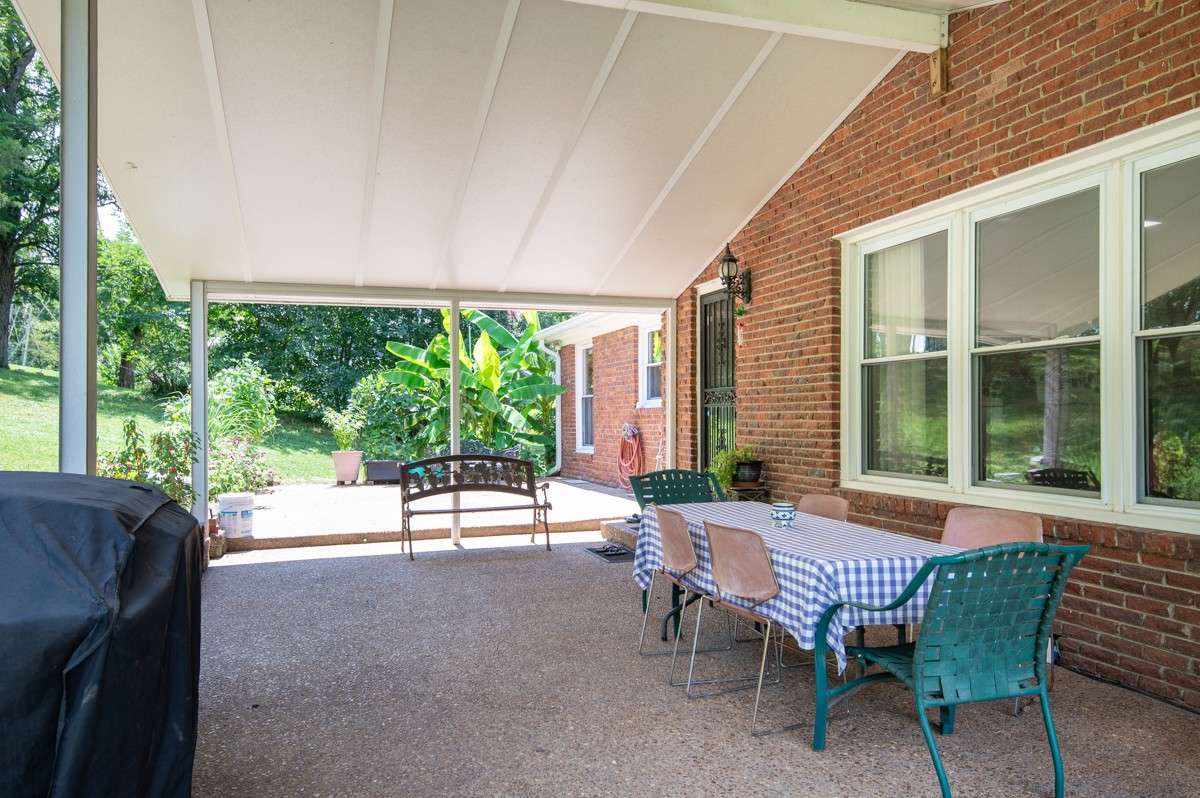 Backyard oasis featuring a covered patio, lush landscaping, and a seamless walkway leading to the pool—perfect for relaxing or entertaining outdoors.